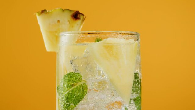 Pineapple lemonade on orange background. Fruit ananas cocktail close-up texture, healthy sweet drink. Detox drinking, summer refreshment concept.