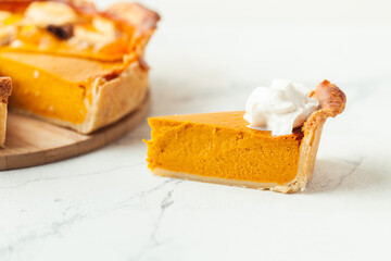 Cut slice of pumpkin pie close up on white background. Autumn orange cake - obrazy, fototapety, plakaty
