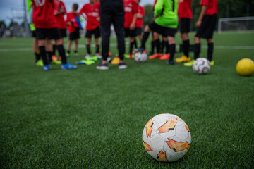 Obraz na płótnie Canvas Children during a football match listen to the coach's directives, close-up on the football ball