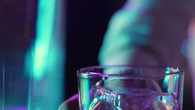 The bartender professionally throws ice into the glass