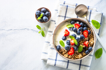 Greek Yogurt with granola and fresh berries at marble table. Top view with copy space.