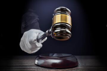 Auctioneer's hand, salesperson holding gavel at public auction. Close up view barker in formal elegant suit with auction hammer for close the bidding