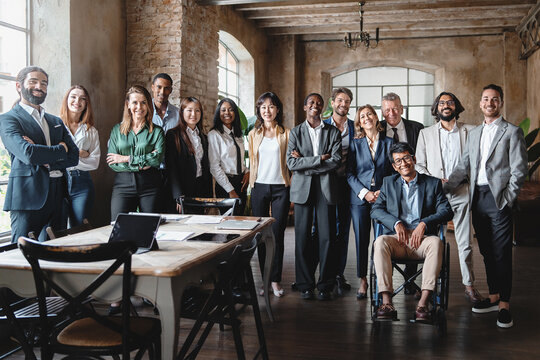 Corporate portrait of a multigenerational working team with multiracial and disabled members - Group photo of colleagues standing in the office in co-working space - business lifestyle concept.