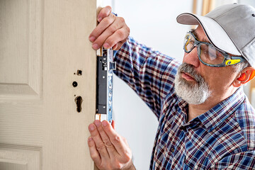 Door lock installation, repair, or replacement service. Door hardware installer locksmith working...