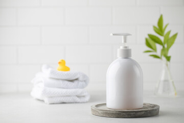Obraz na płótnie Canvas Mockup of a white dispenser with a cosmetic product such as soap, shower gel, with a little duck and white towels