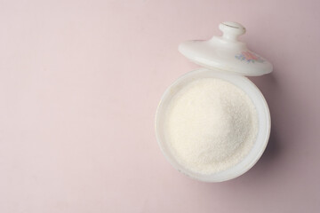 white sugar and spoon in a container on black background,
