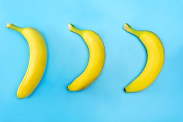 Three ripe bananas on a bright blue background.