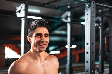 Fototapeta na wymiar Portrait of a sweaty and muscular man smiling while looking in the room . Concept of: proper feeding, exercise, gym and fitness..