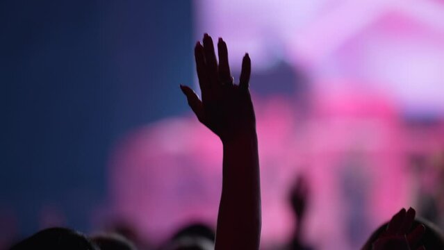 Woman's hand raised while worshiping in a large church.