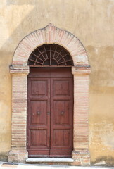 Fototapeta na wymiar Old Wooden Door with Arch Brickwork and Ironwork in Perugia, Umbria, Italy