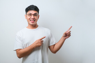 Young handsome asian man wearing casual shirt with a big smile on face, pointing with hand finger to the side looking at the camera.