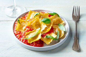 Ravioli with tomato sauce and fresh basil leaves on a plate, Italian dinner