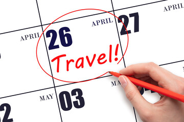 Hand drawing a red circle and writing the text TRAVEL on the calendar date 26 April. Travel planning.