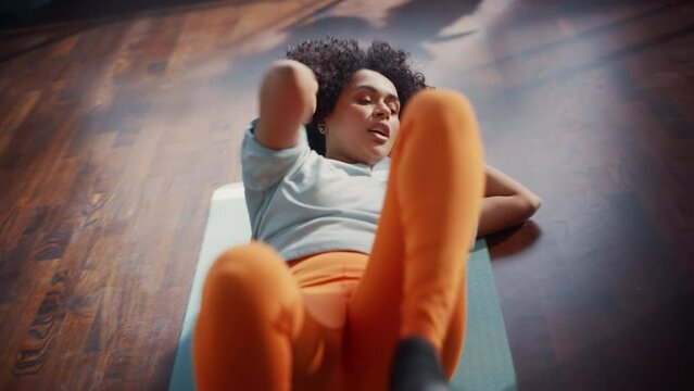 Black Athletic Fit Female Doing Crisscross Crunch Exercises at Home in Her Sunny Living Room. Woman Doing Workout Fitness Abdominal Exercises. Dynamic Cinematic Handheld Shot