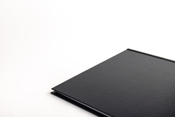 Black notebook is in a closed state. Close up isolated on white background.