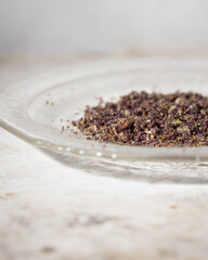 Ground up cannabis bud on a glass plate with light neutral background