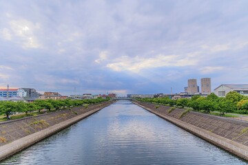 Fototapeta na wymiar 千葉県浦安市境川の橋の上から眺める空と雲の隙間から射す陽光