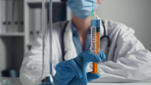 Doctor in mask, white coat holds syringe inscription Smallpox. Monkeypox is virus transmitted to humans from animals Symptoms similar to smallpox. Monkey includes variola, vaccinia, vaccinia viruses