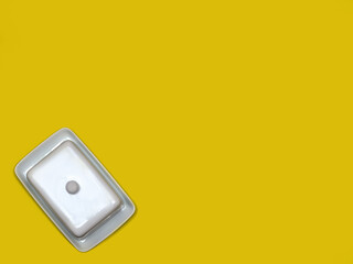 White china butter dish on bright yellow background with copy space.  Flat lay
