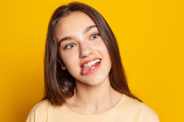 Fototapeta premium Funny girl making face, grimaces isolated on yellow background. Concept of beauty, art, education, youth and emotions