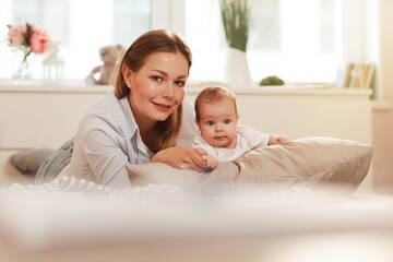 Fototapeta na wymiar Happy young pretty Caucasian woman spending time with little baby girl at home