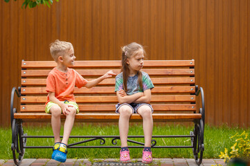 Boy and girl sitting on a bench. On a sunny summer day, a five-year-old boy and a girl are sitting...