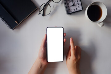 Mockup picture of business woman’s hands holding smart phone with white blank screen in modern place