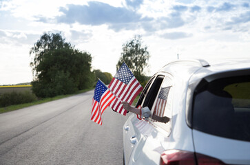 two American flags hanging out of the car window. USA Independence Day July 4th. Pride, freedom,...