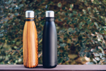 Reusable eco-friendly stainless steel thermo bottles against green nature summer background. Copy...