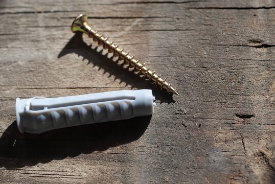 A dowel, mansory plug and a screw on wooden background, home DIY concept