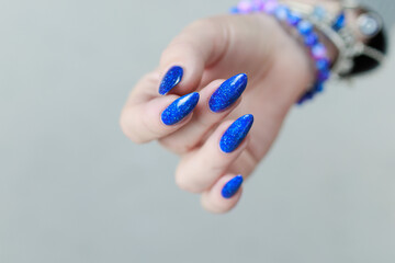 Female hand with long nails and a bottle of light blue color nail polish