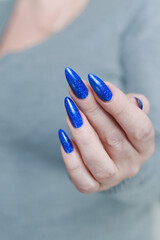 Female hand with long nails and a bottle of light blue color nail polish