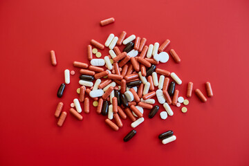 Flat lay different colorful Medical pills on red background,  Vitamin deficiency, avitaminosis concept, assorted pharmaceutical medicine pills, Dietary supplement healthcare product.