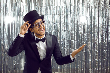 Man in tux dinner jacket, bow tie, top hat and extravagant glasses standing with happy joyful...