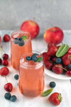 Blurred image of summer refreshing drinks in glass glasses and fruits on a light background.