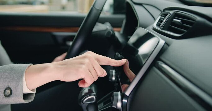 Close up of female hand driver entering an address into the navigation system in modern car. Female hand touches navigation on car monitor screen