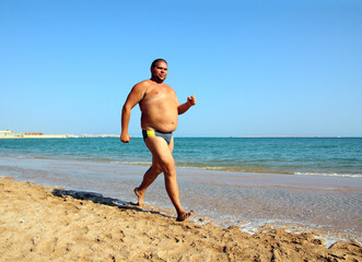 Fototapeta na wymiar overweight man running on beach
