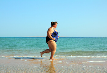 overweight woman running on beach, body positive