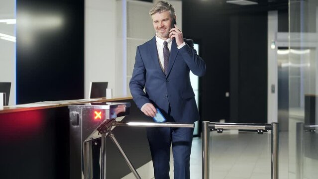 Man worker walks through a Automatic security turnstile station in office. employee entrepreneur pass over in. Businessman enter the business center indoors. holding electronic entrance gate card