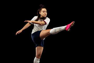 Obraz premium One caucasian energetic woman, soccer, football player in motion isolated on dark background. Sport, action, competitions, games and fitness concept