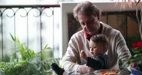 Casual grand-father holding baby infant at balcony. Candid grand-parent with toddler grand-son