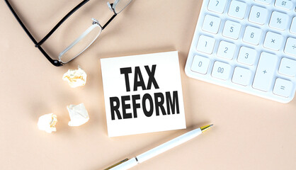 TAX REFORM question text on sticky with pen ,calculator and glasses on a beige background