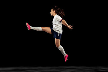One caucasian energetic woman, soccer, football player in motion isolated on dark background. Sport, action, competitions, games and fitness concept