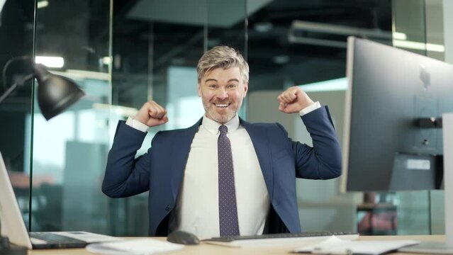 Happy mature bearded Business Man Employee Working on pc computer Celebrates Successful YES Gesture. Working in moderm office Stroke of Luck, Wins Big. Senior worker victory good news financial deal