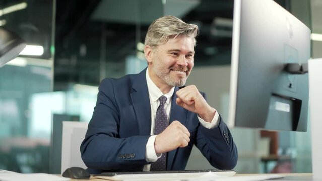 Happy mature bearded Business Man Employee Working on pc computer Celebrates Successful YES Gesture. Working in moderm office Stroke of Luck, Wins Big. Senior worker victory good news financial deal