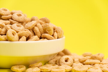 Quick cereal breakfast in the form of rings on a plate on a yellow background
