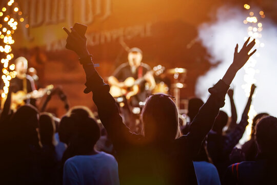 Happy crowd with raised hands at a rock concert.