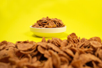 Close-up of wheat flakes on yellow background, quick cereal healthy breakfasts.