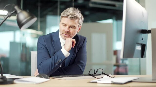 Angry mature business man executive working on computer in office. Upset employee entrepreneur frustrated Looks at the monitor screen. nervous breakdown breaks shouting Stressful sitting at desk