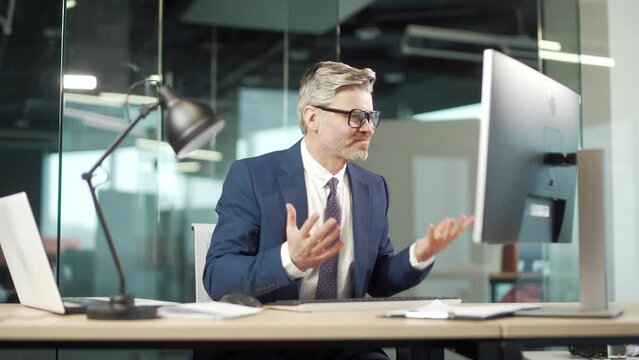 Angry mature business man executive working on computer in office. Upset employee entrepreneur frustrated Looks at the monitor screen. nervous breakdown breaks shouting Stressful sitting at desk